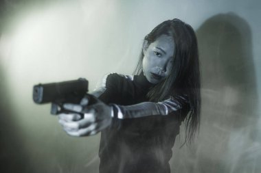 Çekici ve tehlikeli kadın ajanın sinematik portresi. Casus ajan ya da elinde silah tutan Asyalı Koreli gangster kız. Hollywood film tarzında ateşli bir şekilde silahı doğrultuyor.