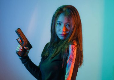 Çekici ve tehlikeli kadın ajanın sinematik portresi. Casus ajan ya da elinde silah tutan Asyalı Koreli gangster kız. Hollywood film tarzında ateşli bir şekilde silahı doğrultuyor.