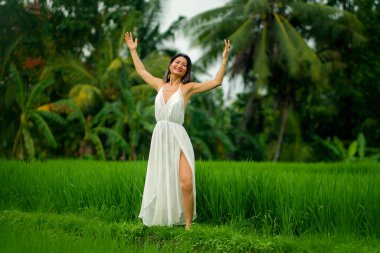 Orta yaşlı, çekici ve mutlu, yaz elbiseli Koreli kadın tropikal dans pistinin keyfini çıkarıyor.