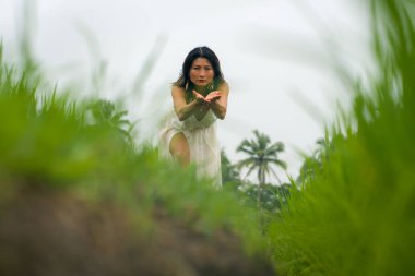 Doğa ile zihin ve beden bağlantısı - Orta yaşlı, çekici ve mutlu, yaz elbiseli Asyalı kadın, tropikal varış noktasında dans ediyor.