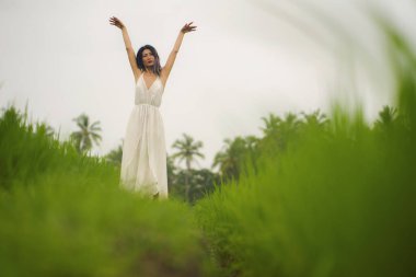 Orta yaşlı, çekici ve mutlu yaz elbiseli Asyalı kadın tropikal dans pistinin keyfini çıkarıyor.