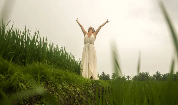 body and mind connection with nature - happy and beautiful Asian Chinese woman doing yoga and meditation exercise outdoors at idyllic green rice field enjoying tropical Summer holidays