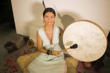 ses iyileştirme ve meditasyon terapisi - çekici ve zarif Asyalı Çinli şifacı kadın yoga stüdyosunda rahatlama egzersizi ve sağlıklı yaşam tarzı olarak davul çalıyor.