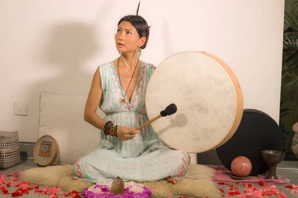 sound healing and meditation therapy - attractive and elegant Asian Chinese healer woman playing drum at yoga studio as relaxation exercise in wellness and healthy lifestyle