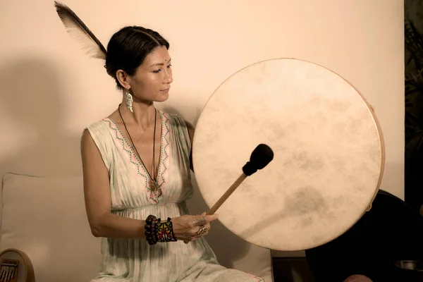 sound healing and meditation therapy - attractive and elegant Asian Chinese healer woman playing drum at yoga studio as relaxation exercise in wellness and healthy lifestyle