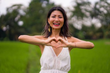 Açık havada tatil portresi. Orta yaşlı, çekici, beyaz elbiseli Asyalı bir kadın. Özgürlüğün ve doğanın tadını çıkarıyor.