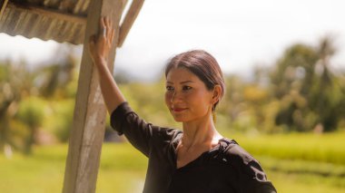 Çekici ve mutlu Asyalı Çinli kadın portresi 40 'lı ya da 50' li yaşlarda. Yaz tatilleri boyunca tropikal pirinç tarlasında heyecanlı ve kaygısız bir şekilde eğleniyor.