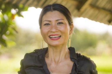 Çekici ve mutlu Asyalı Çinli kadın portresi 40 'lı ya da 50' li yaşlarda. Yaz tatilleri boyunca tropikal pirinç tarlasında heyecanlı ve kaygısız bir şekilde eğleniyor.