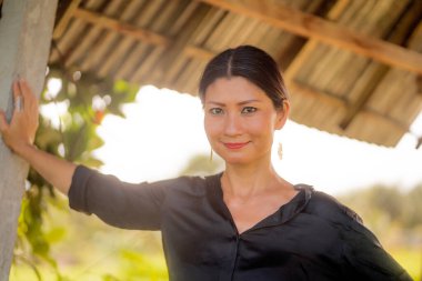 Çekici ve mutlu Asyalı Koreli kadın portresi 40 ya da 50 'li yaşlarda. Yaz tatilleri boyunca tropikal pirinç tarlasında heyecanlı ve kaygısız bir şekilde eğleniyor.