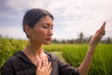 Pirinç tarlasında açık havada yoga ve meditasyon - çekici ve mutlu orta yaşlı Asyalı Çinli kadın sağlıklı yaşam tarzı ve sağlıkla ilgili olarak yoga ve rahatlamanın tadını çıkarıyor.