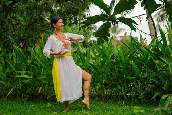 mind and body connection - beautiful and happy healer Asian woman holding incense cup doing ritual traditional healing dance at green tropical forest in wellness and healthy lifestyle