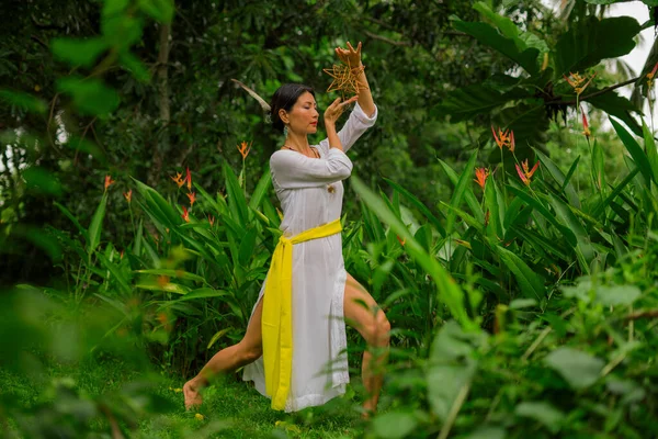 mind and body connection - beautiful and happy healer Asian woman holding incense cup doing ritual traditional healing dance at green tropical forest in wellness and healthy lifestyle