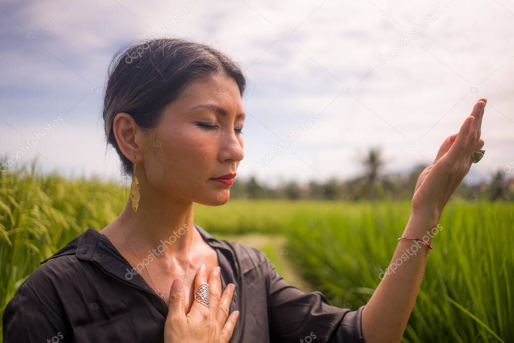 outdoors yoga and meditation at rice field - attractive and happy middle aged Asian Chinese woman enjoying yoga and relaxation in connection with the nature in healthy lifestyle and wellness