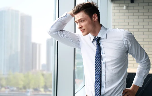 Hombre de negocios guapo mirando por la ventana —  Fotos de Stock