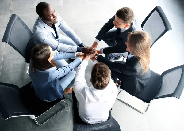 Yaratıcı iş ekibi ofiste el ele tutuşuyor.