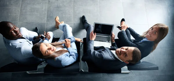 Grupo de jóvenes empresarios atractivos sentados en las sillas usando un ordenador portátil —  Fotos de Stock