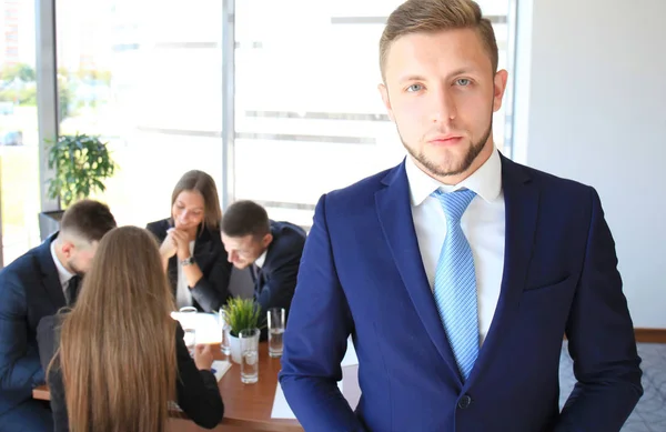 Affärsman med kollegor i bakgrunden på kontoret — Stockfoto