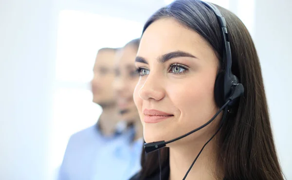 Portret van callcenter medewerker vergezeld door haar team. Lachende klant support operator aan het werk. — Stockfoto