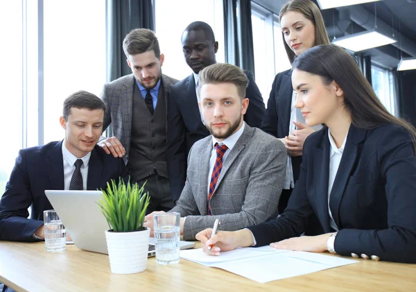 Brainstorming. Groupe de gens d'affaires regardant l'ordinateur portable ensemble. Un homme d'affaires regardant la caméra . — Photo