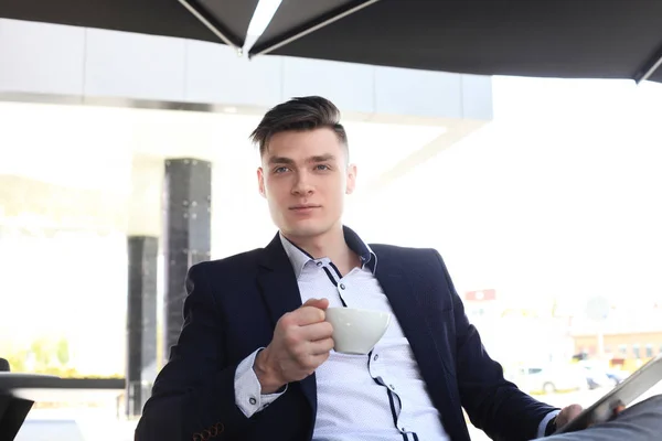 Retrato de un hombre de negocios confiado sentado en el banco y tomando café al aire libre . — Foto de Stock