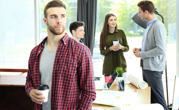 Jovem empresário atraente feliz bebendo café no escritório . — Fotografia de Stock