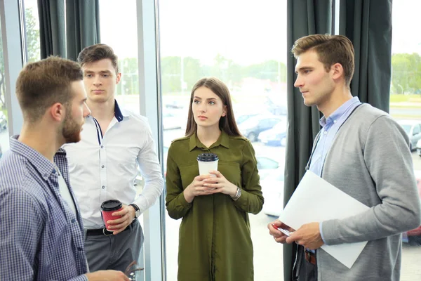 Grupo de jóvenes modernos en ropa casual inteligente que tienen una reunión de tormenta de ideas en la oficina creativa. — Foto de Stock