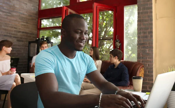 Retrato de um empresário afro-americano feliz exibindo computador no escritório . — Fotografia de Stock