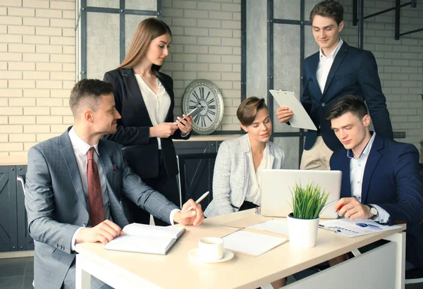 Brainstorming. Un gruppo di uomini d'affari che guardano insieme il portatile. Una donna d'affari guardando la macchina fotografica . — Foto Stock