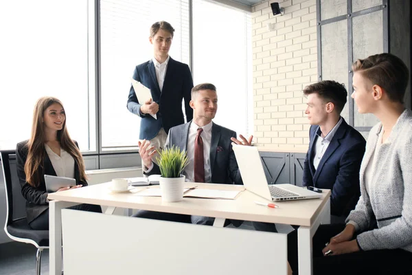 Brainstorming. Groupe de gens d'affaires regardant l'ordinateur portable ensemble. Une femme d'affaires regardant la caméra . — Photo