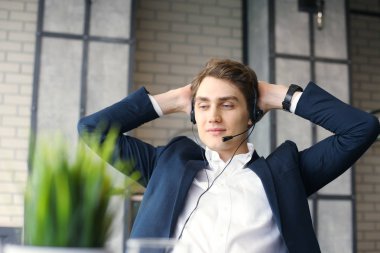 Gülümseyen yakışıklı genç erkek çağrı merkezi operatörü.