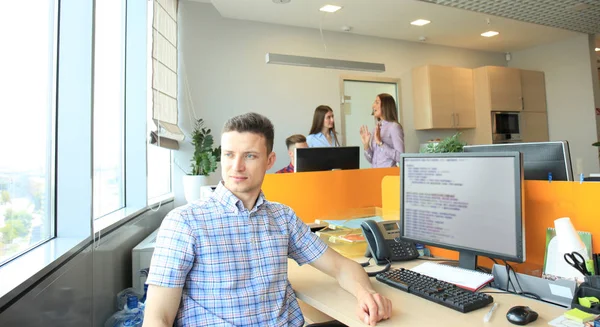 Красивый бизнесмен в повседневной одежде на фоне своих партнеров в креативном офисе . — стоковое фото