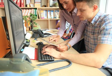 Group of young modern people in smart casual wear having a brainstorm meeting while standing in the creative office. clipart