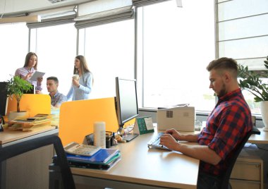 Akıllı telefon tutarak ve onun çalışma evinde otururken bakarak yakışıklı genç gözlük.