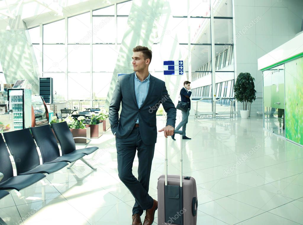 Business man with suitcase in hall of airport.