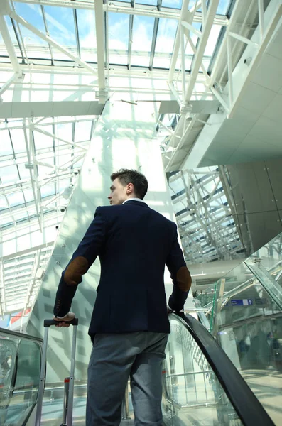 Empresario en el aeropuerto bajando por la escalera mecánica . —  Fotos de Stock