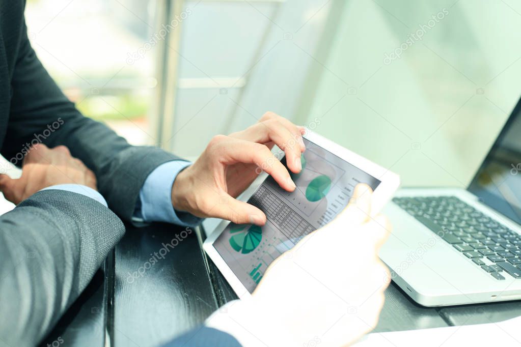 Business person analyzing financial statistics displayed on the tablet screen.