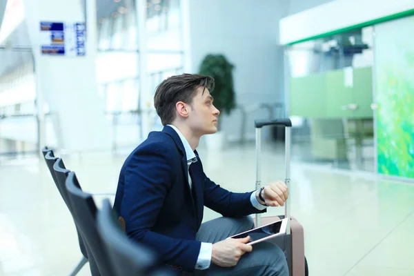 Empresário verificando o tempo e usando tablet no aeroporto . — Fotografia de Stock