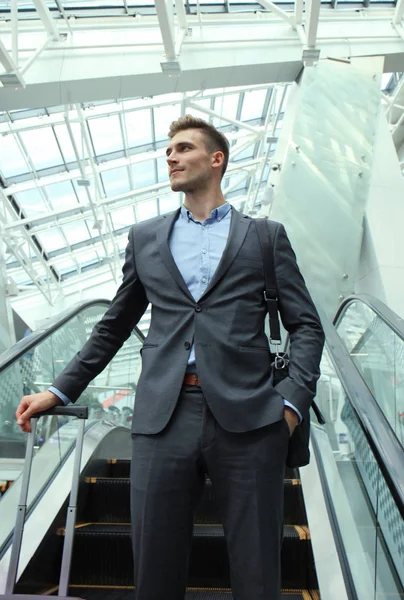 Empresario en el aeropuerto bajando por la escalera mecánica . — Foto de Stock