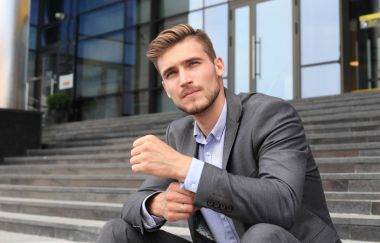 Bir bina dışında merdivenlerde oturan yakışıklı erkek iş yürütme.