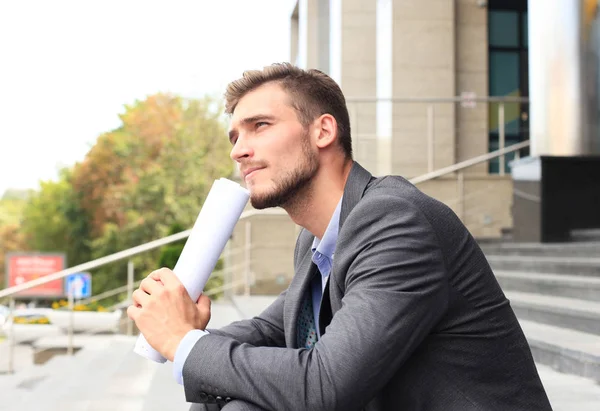 Charmant homme d'affaires assis dans les escaliers devant un immeuble . — Photo