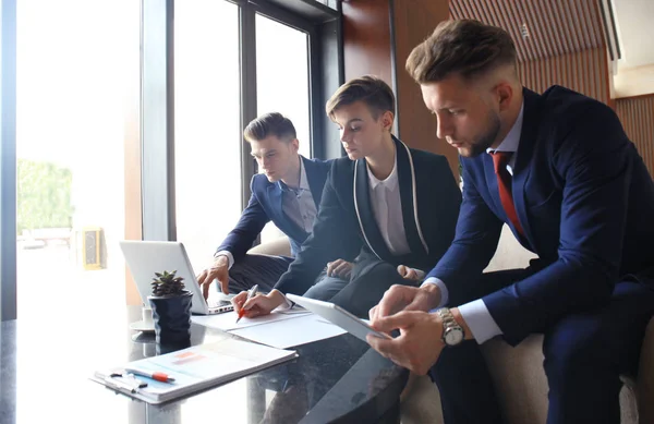 Girişim ekibi, modern parlak ofis içi beyin fırtınası, dizüstü bilgisayar ve tablet bilgisayar üzerine toplantı üzerine çalışıyor.