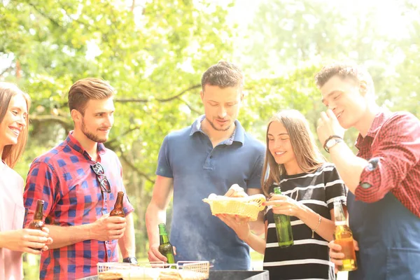 Ευτυχισμένοι φίλοι ψήνοντας κρέας και απολαμβάνοντας μπάρμπεκιου σε εξωτερικούς χώρους. — Φωτογραφία Αρχείου