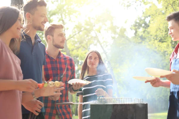 Happy friends grilling meat and enjoying barbecue party outdoors. — Stock Photo, Image