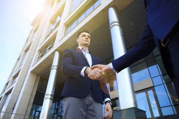 Empresários apertando as mãos fora do edifício de escritórios moderno . — Fotografia de Stock