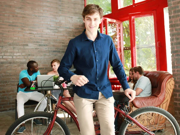 近代的なオフィスに自転車に座っている若い男. — ストック写真