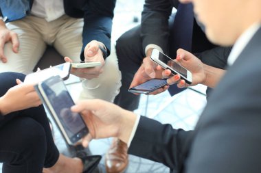 Toplantıda oturup akıllı telefonlar kullanan kişiler, grup, ellerinde yakın çekim.