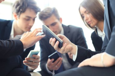 Toplantıda oturup akıllı telefonlar kullanan kişiler, grup, ellerinde yakın çekim.