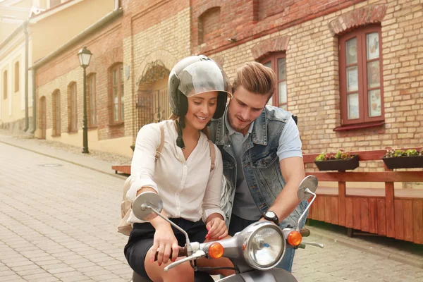 Feliz joven pareja montando scooter en la ciudad. Un chico guapo y una joven viajan. Concepto aventura y vacaciones . — Foto de Stock
