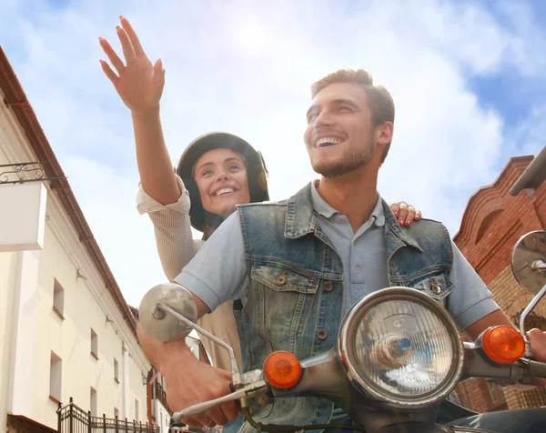 Feliz joven pareja montando scooter en la ciudad. Un chico guapo y una joven viajan. Concepto aventura y vacaciones . — Foto de Stock