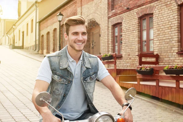陽気な若い男が町でスクーターに乗っています。. — ストック写真